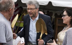 rica Dischino / Tribune Jon Huseby, district engineer with the Minnesota Department of Transportation's District 8, holds some of the gold shovels that he distributed to officials Tuesday as he speaks to attendees of the Willmar Wye groundbreaking ceremony.