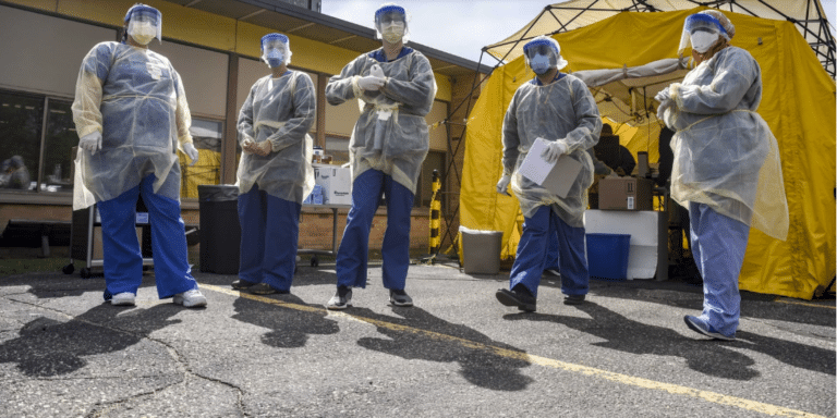 Employees of Jennie-O wear full protective gear and stand outside near a yellow tent readty to test other employees during the pandemic