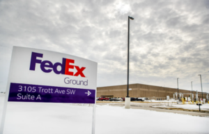 a close up photo of a FedEx sign in winter with the building in the background