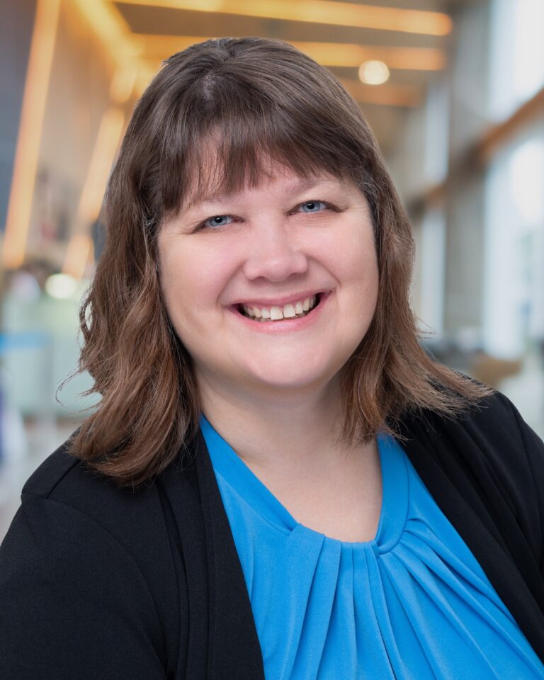 head shot of Michelle, a white woman with brown hair, in a blue shirt and black blazer