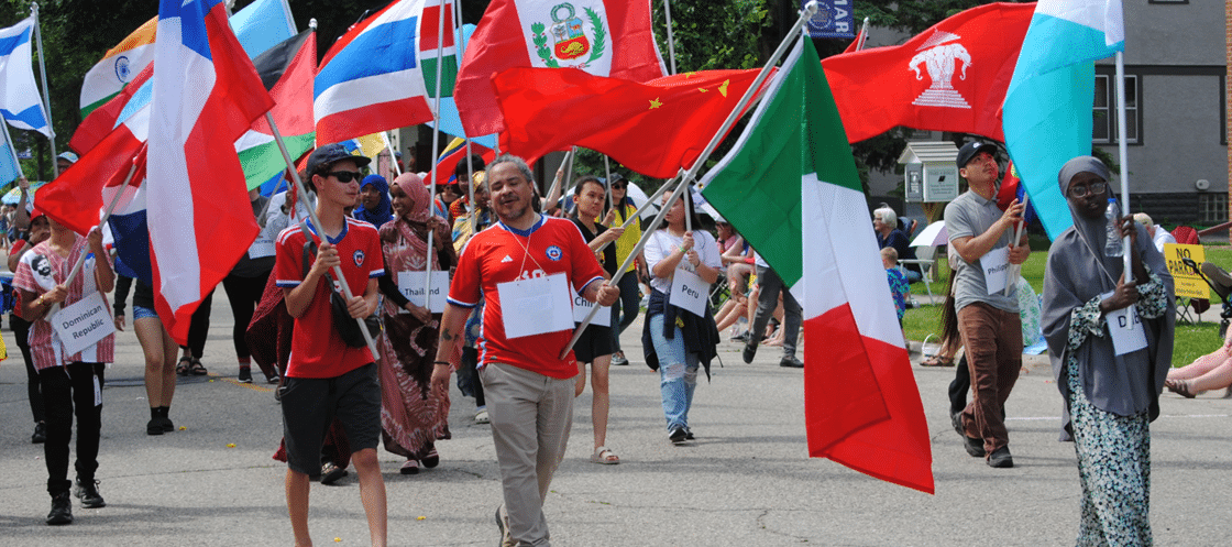People walk in a parade with a variety of flags from different countries