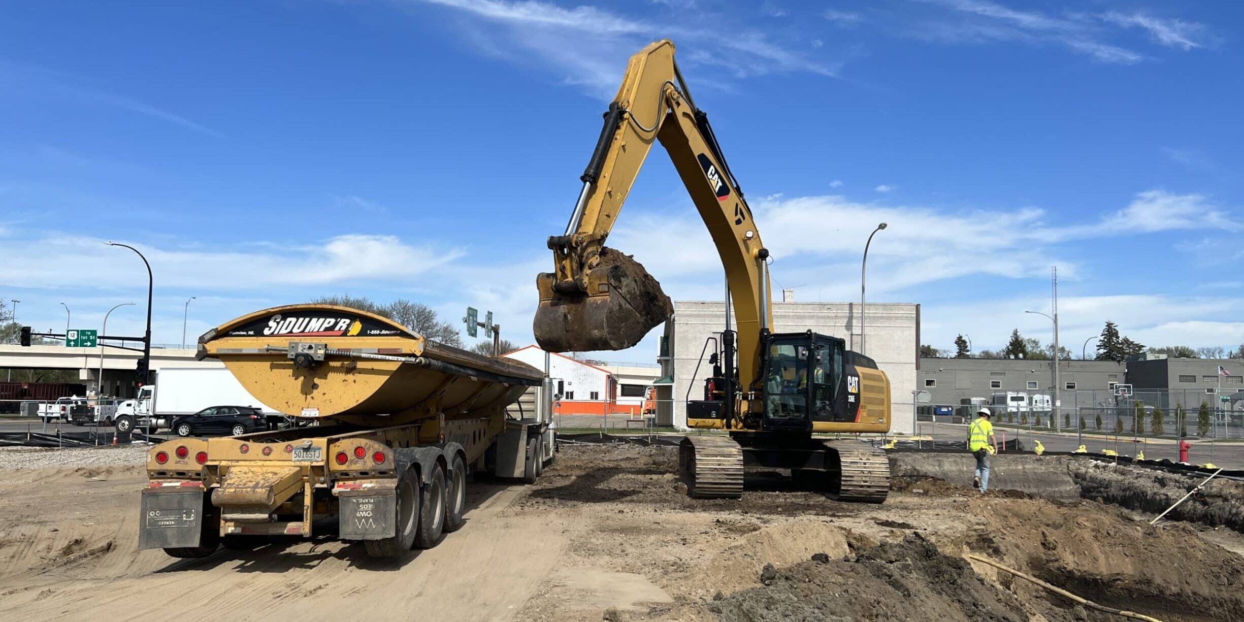 A bulldozer lifts dirt to put into a dump truck