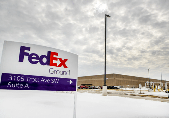 a close up photo of a FedEx sign in winter with the building in the background