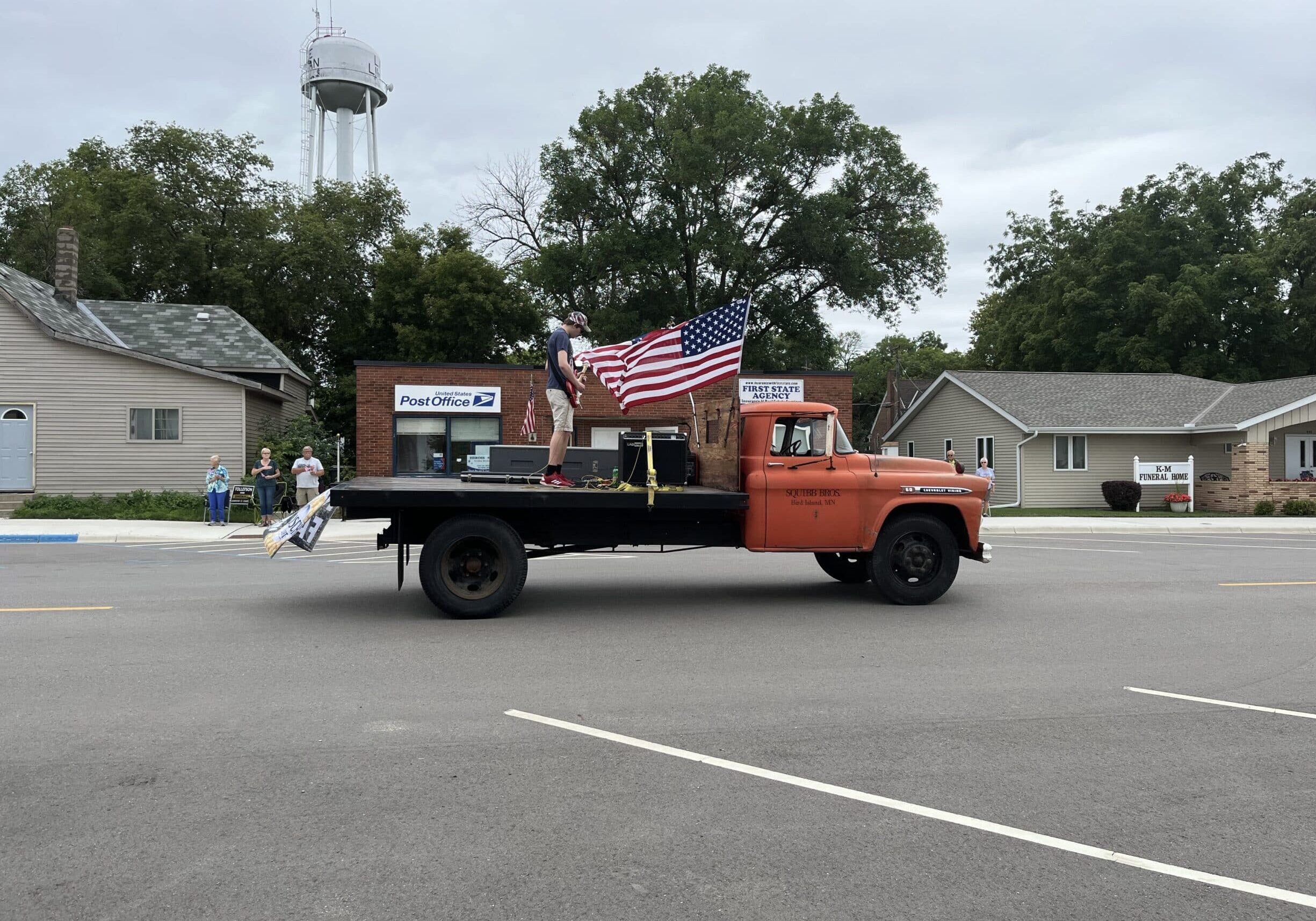 Truck with a flag going down the street at a parade